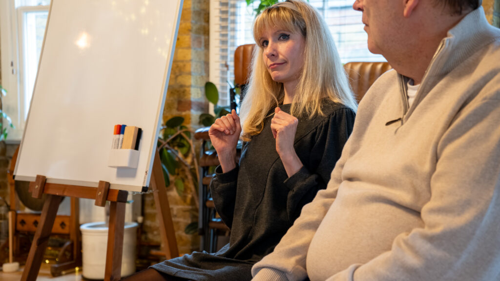 Emma coaching during a Reconnect grief session, with a flip chart and creative studio space in the background